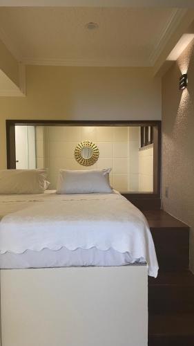 a bedroom with a large white bed with a mirror at Hotel Pousada Azzurra in Natal