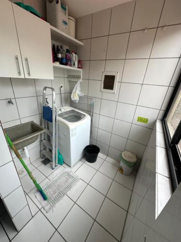 een kleine witte betegelde badkamer met een wasmachine bij APARTs na Litorânea Ferreira Hospedagens in São Luís