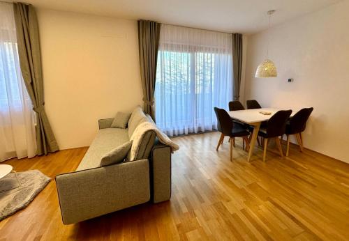 a living room with a couch and a table with chairs at SkiCity Apartment Pohorje Bellevue in Pohorje