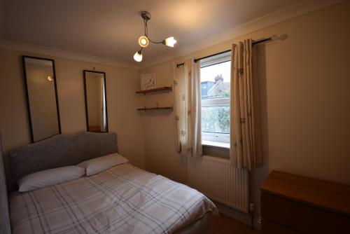 a small bedroom with a bed and a window at Two Bedroom Flat St Andrews Road in London