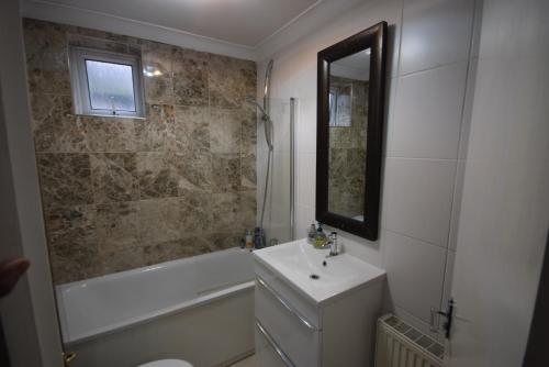 y baño con lavabo, bañera y espejo. en Two Bedroom Flat St Andrews Road en Londres