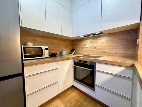 a small kitchen with white cabinets and a microwave at SkiCity Apartment Pohorje Bellevue in Pohorje