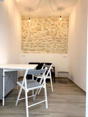 - une table et des chaises blanches dans une chambre dotée d'un mur en pierre dans l'établissement Appartement Secteur Gare et Place de la Comédie, Wifi et Climatisation, à Montpellier