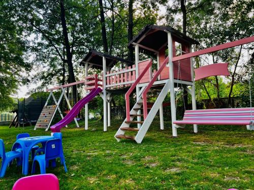 un parque infantil con tobogán y sillas en el césped en Pensiunea Pink House Runcu, en Runcu