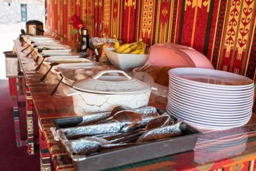 a long buffet with plates and bowls of food at Calm Camp in Wadi Rum