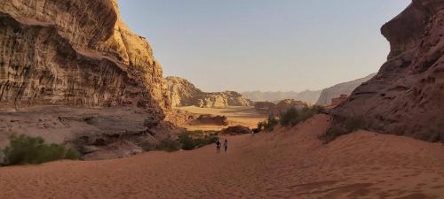 deux personnes marchant dans le désert dans un canyon dans l'établissement Wadi Rum Classic Camp, à Wadi Rum
