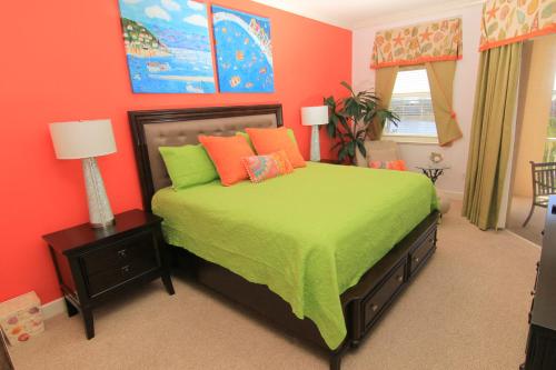 Schlafzimmer mit einem Bett mit grüner Bettwäsche und orangefarbenen Kissen in der Unterkunft Come stroll along the beach and enjoy shared resort style amenities! in Palm Coast