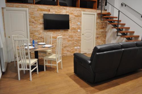 a living room with a table and a black leather couch at Loft Casa Zeffirino in Sanremo