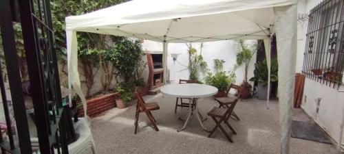 a patio with a table and chairs under a white canopy at Maui Hostel in Mar del Plata