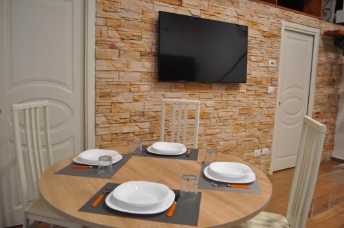 a dining room table with a television on a brick wall at Loft Casa Zeffirino in Sanremo