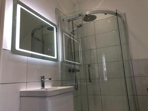 uma casa de banho com um chuveiro, um lavatório e um espelho. em Luxury 6 bedroom retreat in Stratford Upon Avon em Stratford-upon-Avon