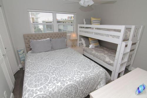 een kleine slaapkamer met een bed en een stapelbed bij Visit this top floor property located on the no-drive beach with 2 complex pools! in New Smyrna Beach