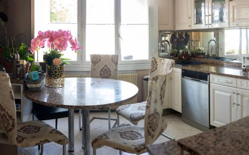 a kitchen with a table and chairs with pink flowers on it at PARADIS CHAMBRES D'HÔTES PROCHE PARIS - AÉROPORT CHARLES DE GAULLE AIRPORT - PARC DES EXPOSITION VILLEPINTE - DYSNAYLAND PARIS. in Tremblay En France