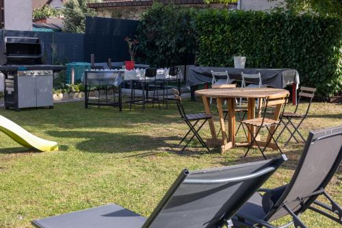 a table and chairs in a yard with a grill at PARADIS CHAMBRES D'HÔTES PROCHE PARIS - AÉROPORT CHARLES DE GAULLE AIRPORT - PARC DES EXPOSITION VILLEPINTE - DYSNAYLAND PARIS. in Tremblay En France