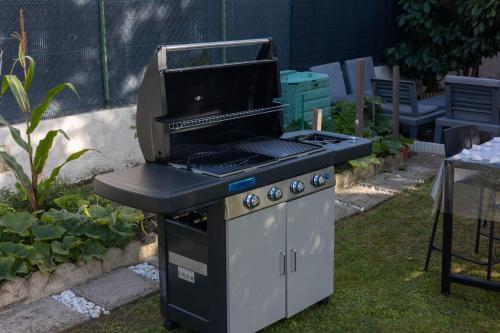 a barbecue grill sitting in the grass in a garden at PARADIS CHAMBRES D'HÔTES PROCHE PARIS - AÉROPORT CHARLES DE GAULLE AIRPORT - PARC DES EXPOSITION VILLEPINTE - DYSNAYLAND PARIS. in Tremblay En France
