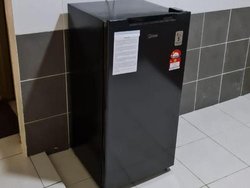 a black refrigerator in a room with a tile wall at Homestay Cinta Furqan 1 - apartment Cameron Highland in Tanah Rata