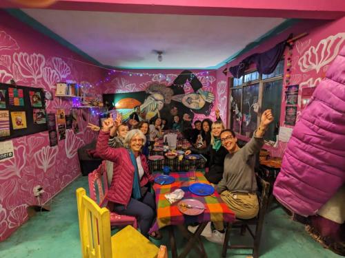 un gruppo di persone sedute a un tavolo con le mani in alto di Historika Hostel Cultural a San Cristóbal de Las Casas