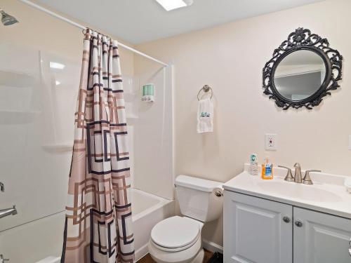 La salle de bains est pourvue de toilettes, d'un lavabo et d'un miroir. dans l'établissement Chardonnay Cottage - GOTL Strip - Cozy & Quaint, à Geneva