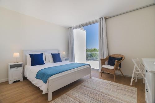 a white bedroom with a bed and a window at Villa Blue Sagres D in Sagres