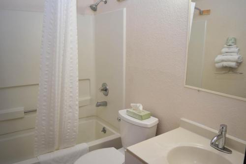 a white bathroom with a toilet and a sink at Corning Inn in Painted Post