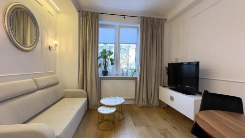 a living room with a white couch and a television at Apartament Centrum Marszałkowska 28 - pl. Zbawiciela in Warsaw