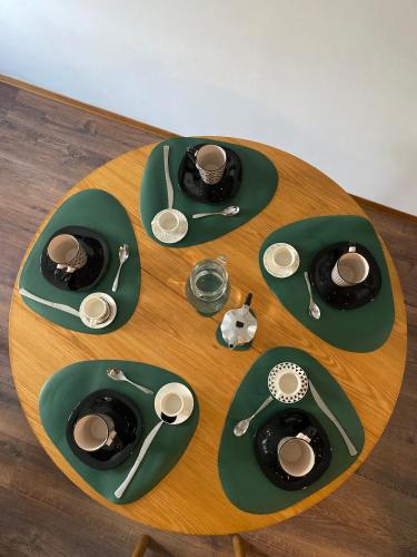 une table en bois avec des assiettes et des cuillères vertes et des gravycteurs dans l'établissement BeSt Camoscio, à Sestrières