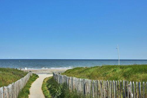 una valla de madera junto a una playa con el océano en Cabourg Plage, en Cabourg