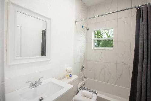 a white bathroom with a sink and a tub at Modern Westshore in Tampa