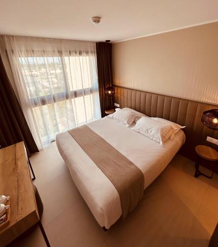a bedroom with a large bed and a large window at Hôtel Spa Restaurant La Madrague in Lucciana
