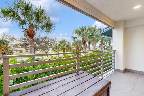 a wooden bench on a balcony with palm trees at Gather Together - Unit 143 in Marco Island