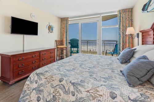 a bedroom with a bed with a television and a balcony at 2501 S Ocean Blvd, 0211 - Ocean Front Sleeps 8 in Myrtle Beach
