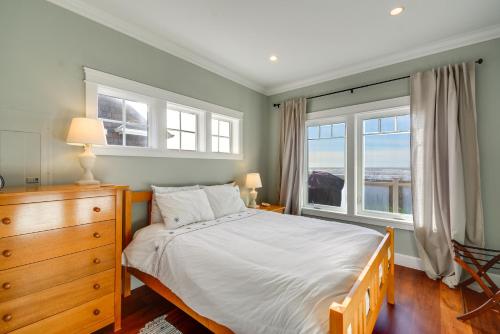 モクリプスにあるOceanfront Moclips Escape with Deck and Beach Access!のベッドルーム1室(ドレッサー付きのベッド1台、窓2つ付)