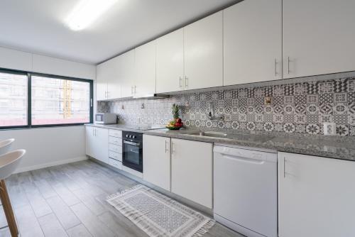 a white kitchen with white cabinets and appliances at Host Wise - Elegant Spacious Flat w Balcony - Ace Location in Vila Nova de Gaia