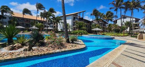 ein Resortpool mit Palmen und Sonnenschirmen in der Unterkunft Taiba Beach Resort in Taíba