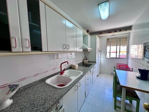 cocina blanca con fregadero y mesa en Apartamento Centrico en Torremolinos, en Torremolinos