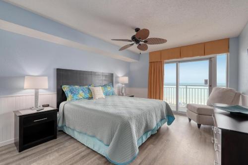 a bedroom with a bed with a ceiling fan and a balcony at 2007 S Ocean Blvd, 0406 - Ocean Front Sleeps 10 in Myrtle Beach