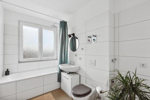 a white bathroom with a sink toilet and a window at Apartment Oase for Four in Merseburg