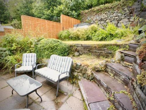 2 sillas y una mesa en un jardín en Country Cottage with Hot-Tub and Cosy Log Burner, en Tregarth
