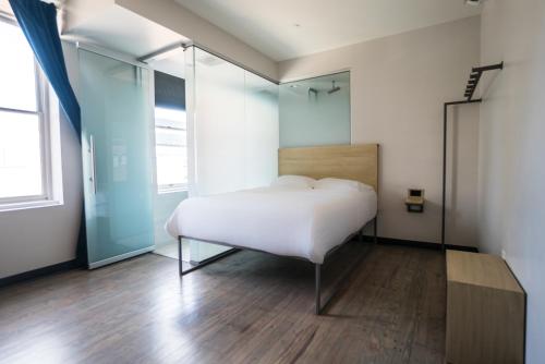 a bedroom with a white bed and a wooden floor at SOVA Micro-Room & Social Hotel in Dallas