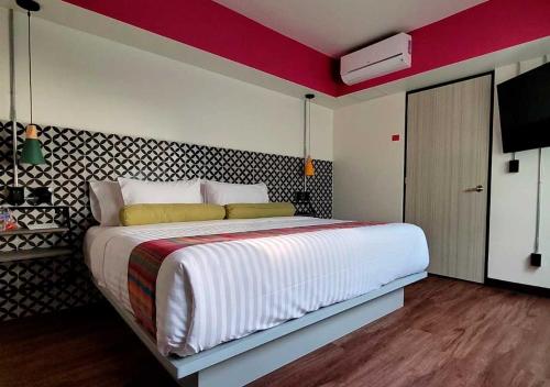 a bedroom with a large bed with a red accent wall at Estancias VIVE MX cuauhtémoc in Mexico City