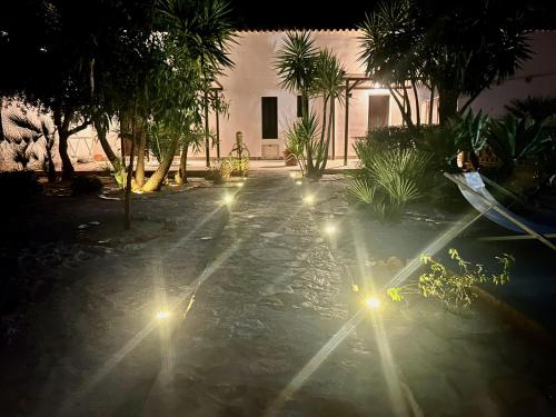 a house with lights in the middle of a yard at L'oasi Una Pineta Sul Mare in Custonaci