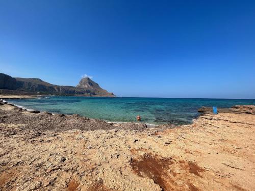 a beach with the ocean and a mountain in the background at L'oasi Una Pineta Sul Mare in Custonaci