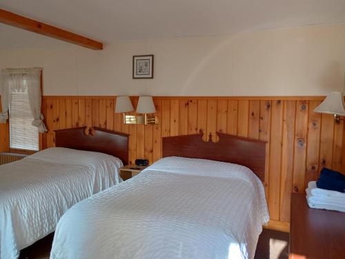two beds in a room with wood paneling at The Ashley in Saranac Lake