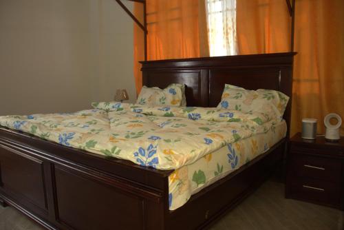 a bed with a wooden headboard and pillows on it at Havana Comfort in Dar es Salaam