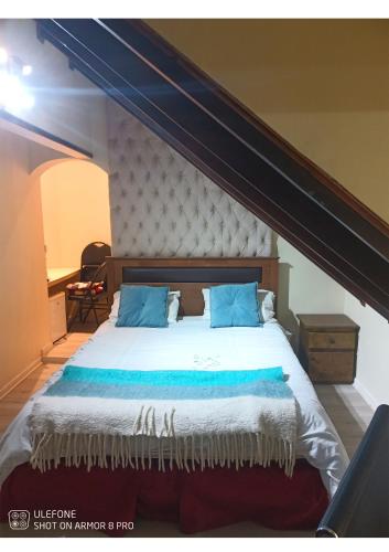 a bedroom with a large bed with blue pillows at Hotel Boutique Castillo del Mar in El Quisco