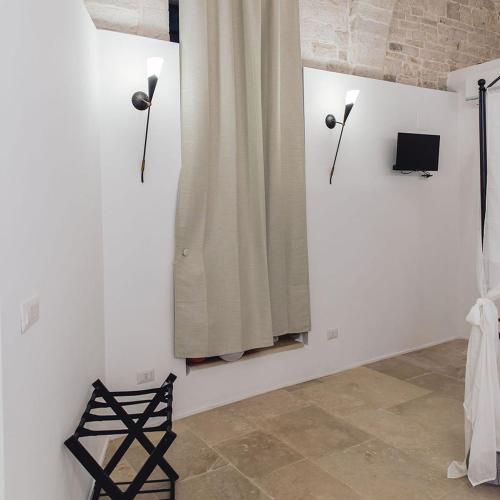 a room with a white wall with two lights and a chair at B&B Rhea Luxury in Terlizzi