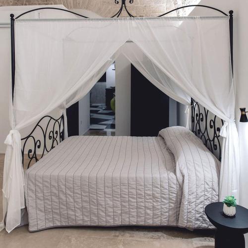 un letto bianco a baldacchino in una camera da letto di B&B Rhea Luxury a Terlizzi