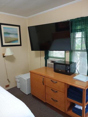 a bedroom with a dresser with a television on it at The Ashley in Saranac Lake
