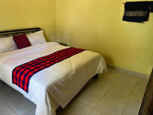 a bedroom with a bed with a red and black striped blanket at Lulunga Eco Lounge and Farm in Narok