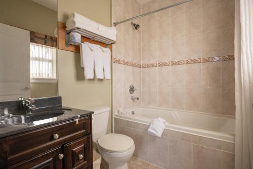 a bathroom with a toilet and a tub and a sink at Days Inn by Wyndham Surrey in Surrey